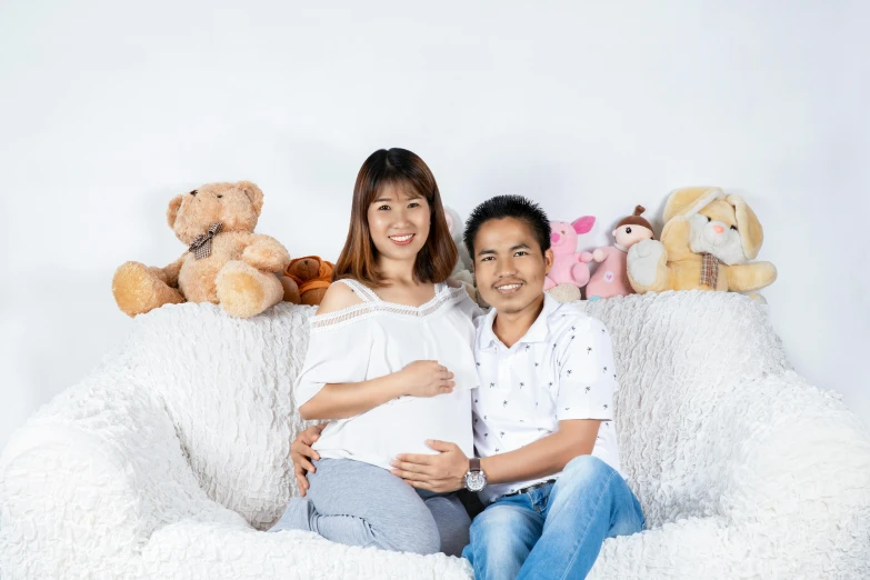 a man and a woman sitting on a bean bag chair, by Tan Ting-pho, pexels contest winner, photorealism, maternal, plain background, background image, maternity feeling