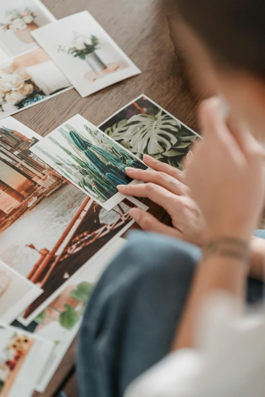 a woman sitting at a table with a bunch of photos, a picture, trending on pexels, plant photography, colour print, inspect in inventory image, close-up photograph
