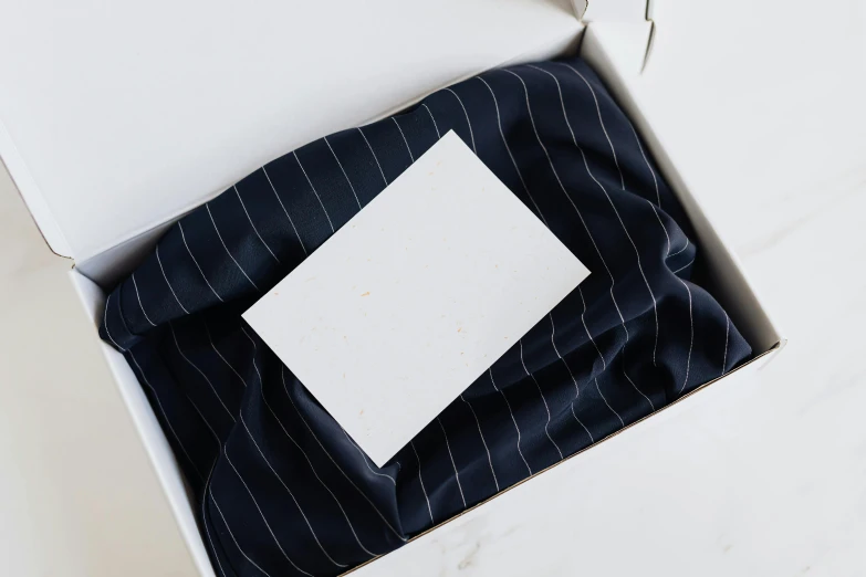 a box that has a piece of paper in it, by Eden Box, unsplash, private press, tailored clothing, striped, ceramic base, navy