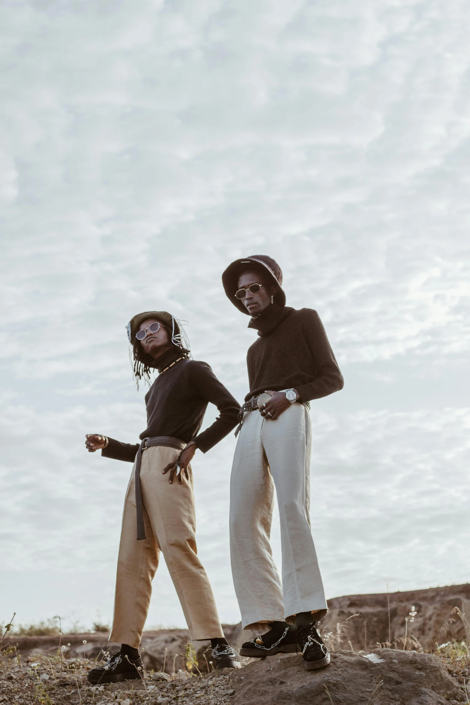 a couple of people standing on top of a hill, trending on unsplash, afrofuturism, dressed in 1970s menswear, neutral colours, young women, pants