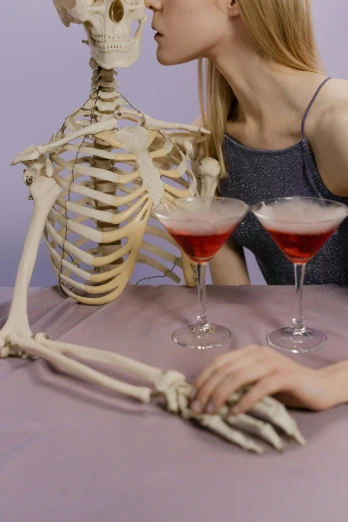 a woman sitting at a table in front of a skeleton, trending on tumblr, drinking a martini, red and purple, rib cage exposed, an aesthetic!