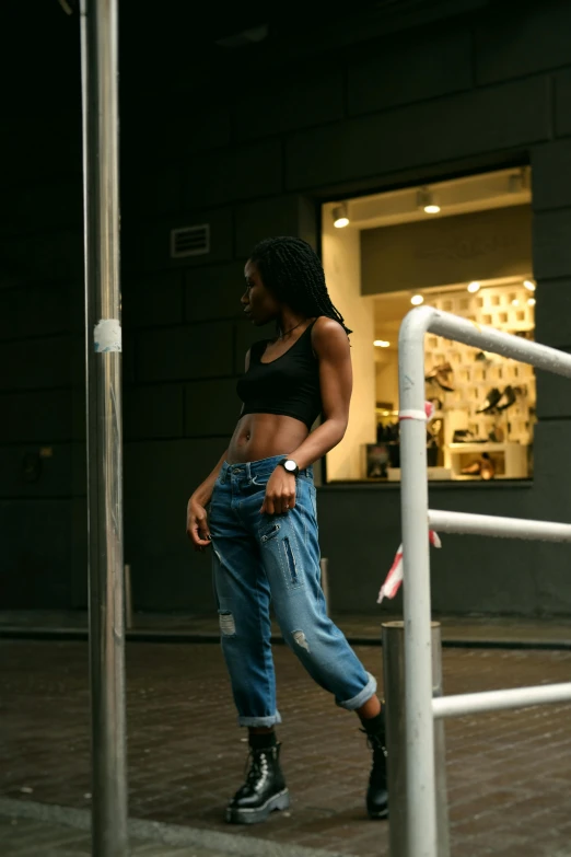 a woman walking down a street next to a pole, pexels contest winner, wearing a crop top, baggy jeans, ( ( dark skin ) ), in a mall