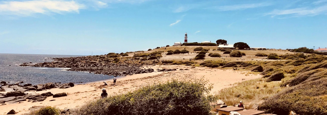 a group of people standing on top of a sandy beach, lighthouse, camilo gc, seen from a distance, summer vibe