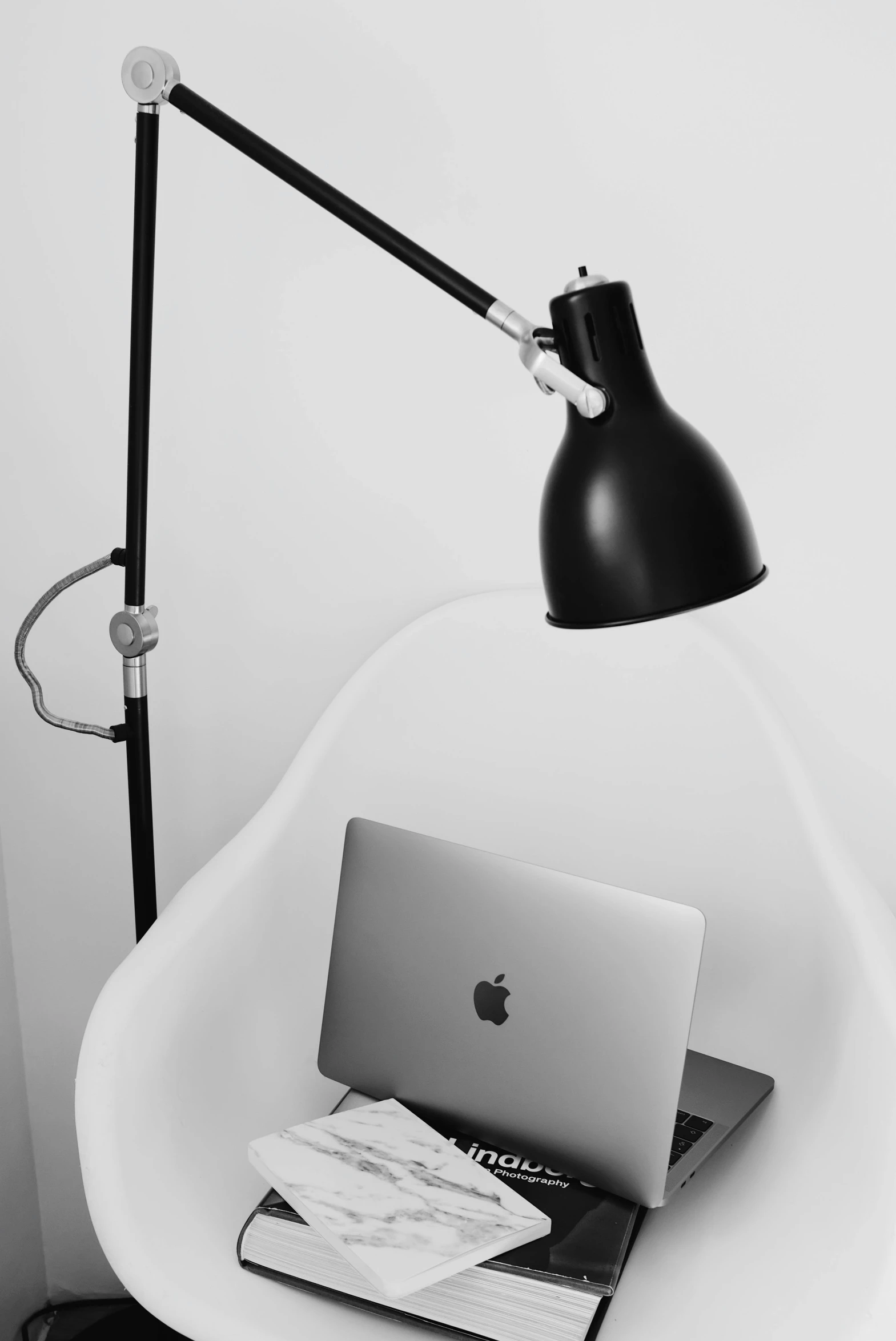 a laptop computer sitting on top of a white chair, a black and white photo, by Romain brook, clamp shell lighting, apple, profile image, lamp