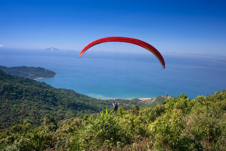 a paraglider flying over the ocean on a sunny day, by Niko Henrichon, unsplash contest winner, sumatraism, mountainous jungle setting, avatar image, vietnam, tamborine