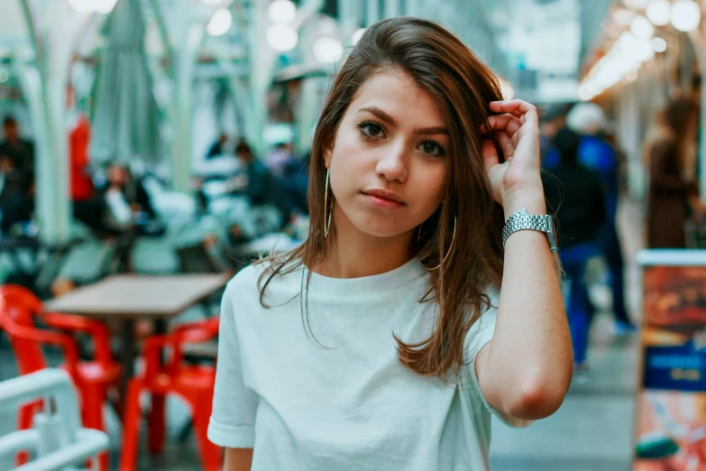 a woman holding a cell phone to her ear, a colorized photo, inspired by Elsa Bleda, pexels contest winner, hyperrealism, dressed in a white t-shirt, brown medium length hair, 🤤 girl portrait, standing in a restaurant