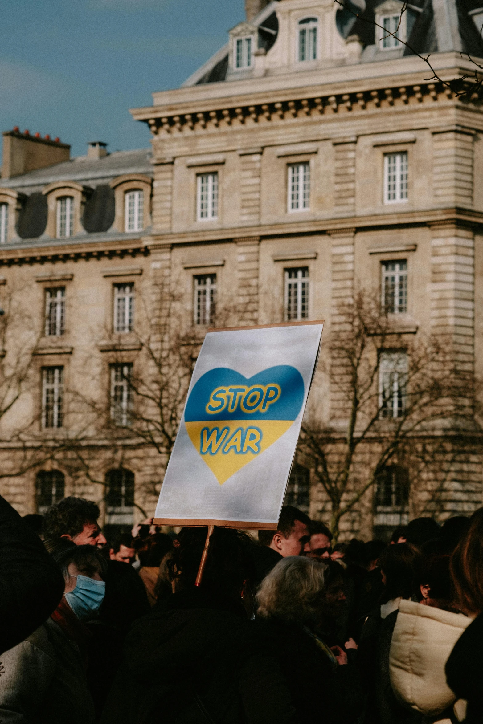 a group of people holding a sign in front of a building, volodymyr zelensky at war, french flag, slide show, feature