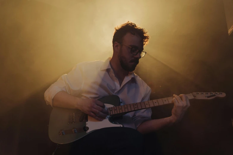 a man playing a guitar in a dimly lit room, photorealism, brandon woelfel, promo image, portrait image, rectangle