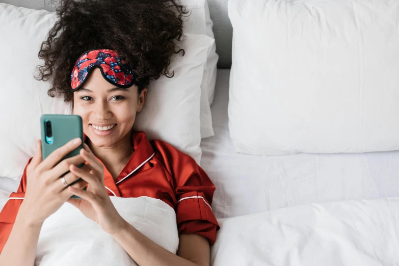 a woman laying in bed with a cell phone, trending on pexels, perfect smile vogue, ashteroth, again and again, hotel room