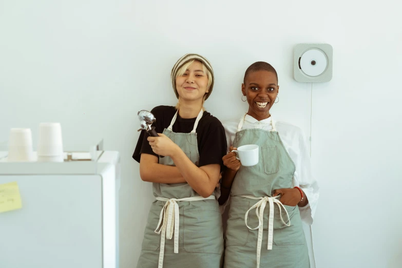 a couple of women standing next to each other, by Lee Loughridge, pexels contest winner, renaissance, starbucks aprons and visors, white, diverse, grey