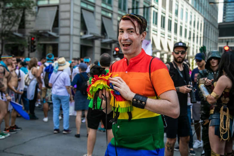 a man in a rainbow shirt is walking down the street, posing for a picture, francois legault, wearing a fancy dress, capital sin of pride