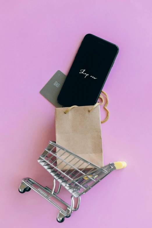 a shopping cart with a phone in it on a pink background, a picture, by Joseph Severn, pexels, square, black, hey, ko-fi