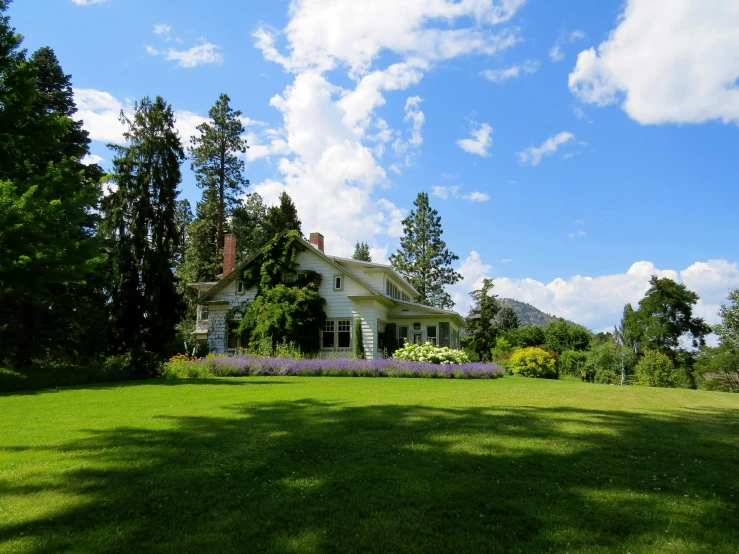 a large white house sitting on top of a lush green field, a picture, british columbia, cottagecore, listing image