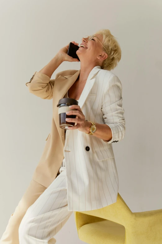 a woman sitting on a chair talking on a cell phone, iced latte, energetic varia suit, wearing a linen shirt, blond