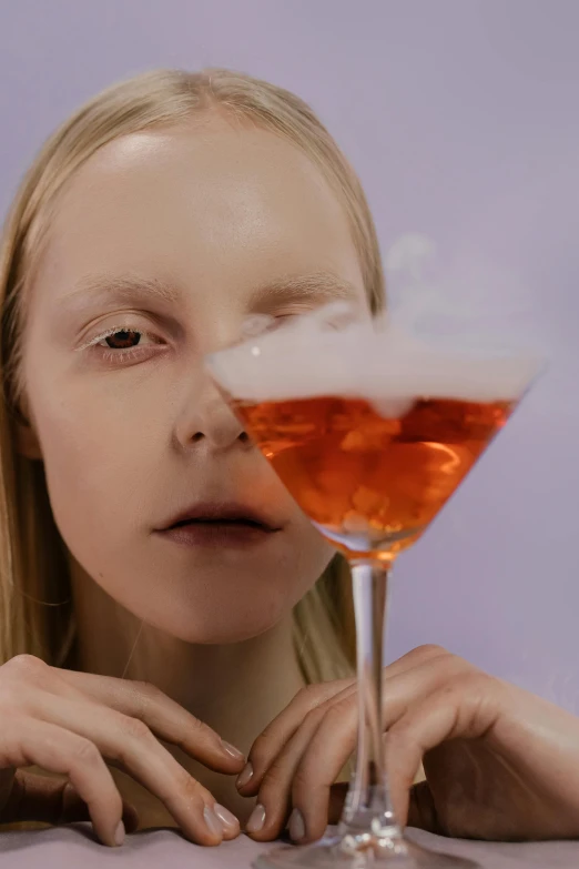 a girl sitting at a table with a drink in front of her face, an album cover, inspired by Méret Oppenheim, trending on unsplash, molecular gastronomy, arper's bazaar, nick knight, a blond