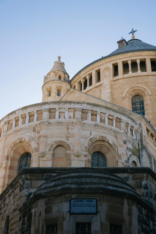 a tall building with a clock on top of it, by Leo Michelson, romanesque, with great domes and arches, stone facade, up-close, rounded roof