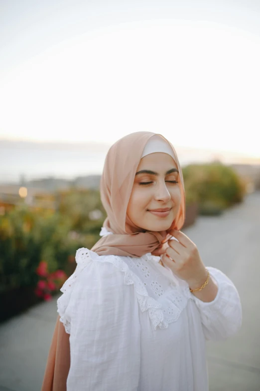 a woman wearing a white shirt and a pink scarf, inspired by Maryam Hashemi, trending on pexels, hurufiyya, at the golden hour, skincare, wearing seashell attire, ☁🌪🌙👩🏾