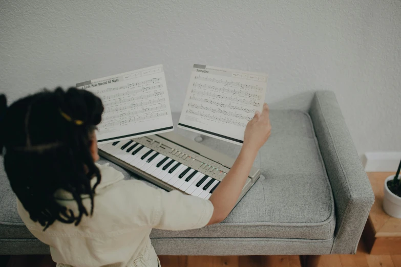 a woman sitting on a couch using a laptop computer, an album cover, pexels contest winner, piano guitar music notes key, school class, ivory and ebony, for junior