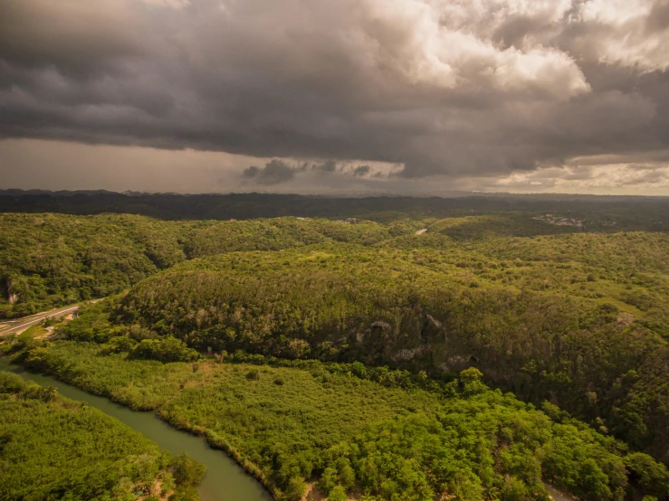 a river running through a lush green forest, pexels contest winner, australian tonalism, thunderclouds in the sky, helicopter view, puerto rico, brown