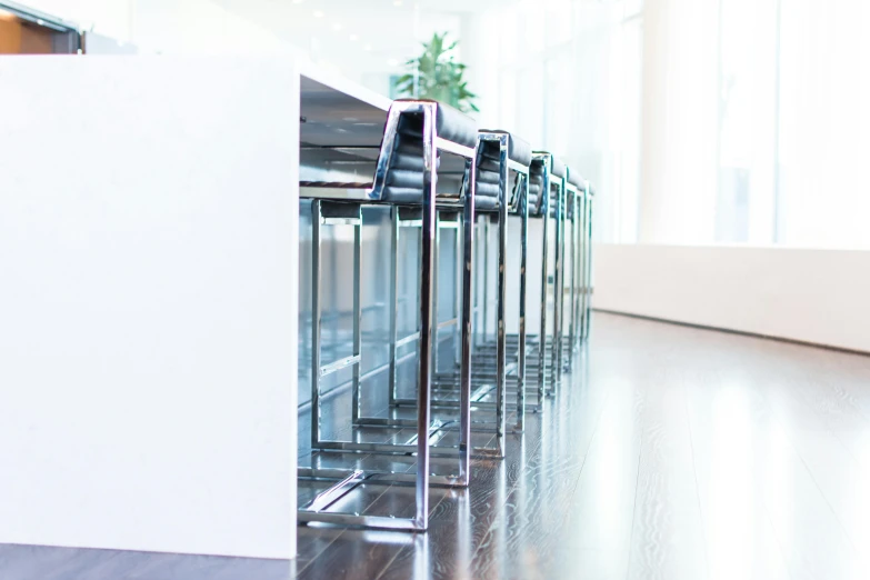 a row of chairs sitting on top of a hard wood floor, inspired by david rubín, unsplash, glass and steel, counter, high-body detail, chrome plated