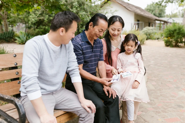 a group of people sitting on top of a wooden bench, caring fatherly wide forehead, young asian girl, standing outside a house, avatar image