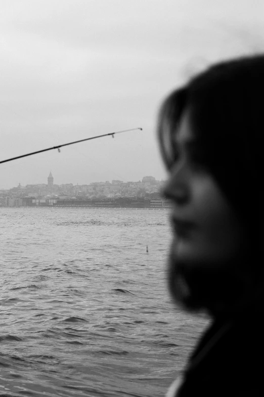 a black and white photo of a man fishing, a black and white photo, by Nabil Kanso, woman's profile, shohreh aghdashloo, looking at the city, half fish