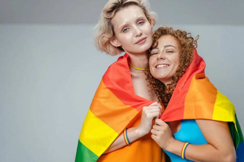 a couple of women standing next to each other, a photo, shutterstock, antipodeans, lgbt flag, cuddling, diverse costumes, femalev beauty