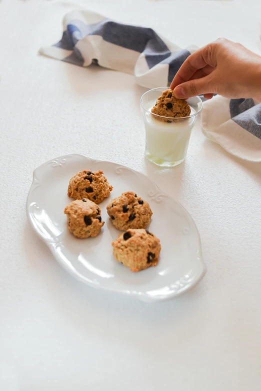 a white plate topped with cookies next to a glass of milk, by Miyamoto, unsplash, renaissance, cannonballs, square, a blond, mid action