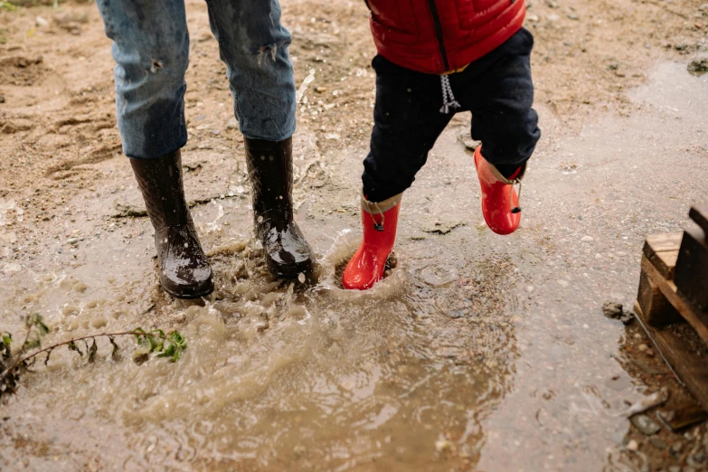a man and a child playing in a puddle of water, pexels, red boots, thumbnail, wearing a red gilet, less detailing