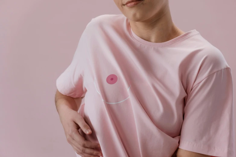 a close up of a person wearing a pink shirt, by Nina Hamnett, belly button showing, graphic tees, half onesided smile, nursing