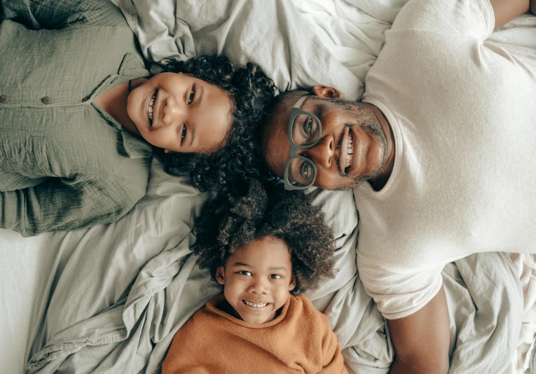 a man, woman and child laying on a bed, pexels contest winner, brown skinned, avatar image, father with child, multi-part