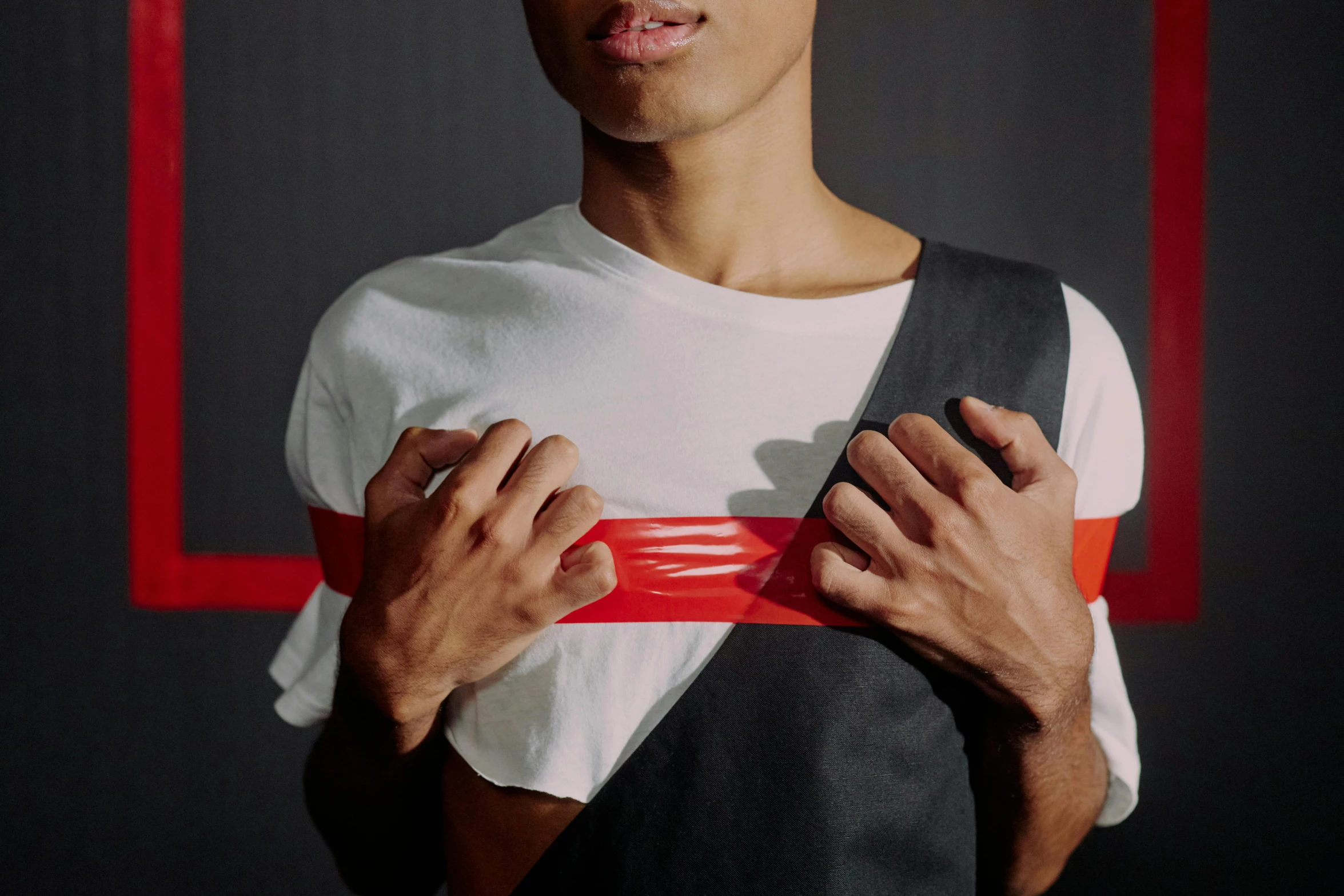 a close up of a person holding a belt, an album cover, pexels contest winner, black shirt with red suspenders, covered in bandages, aida muluneh, thiago lehmann