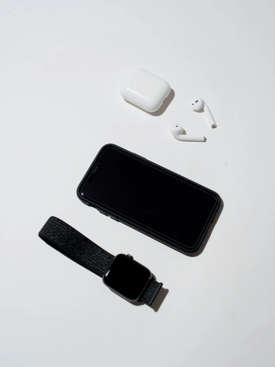 a cell phone sitting on top of a white table, a still life, by Robbie Trevino, airpods, black on black, detailed product image, high resolution image