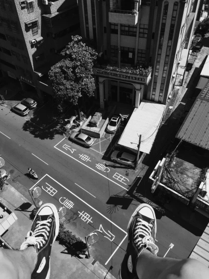 a person standing on top of a tall building, a black and white photo, street art, in the streets of tokyo, sneaker photo, bird\'s eye view, like jiufen