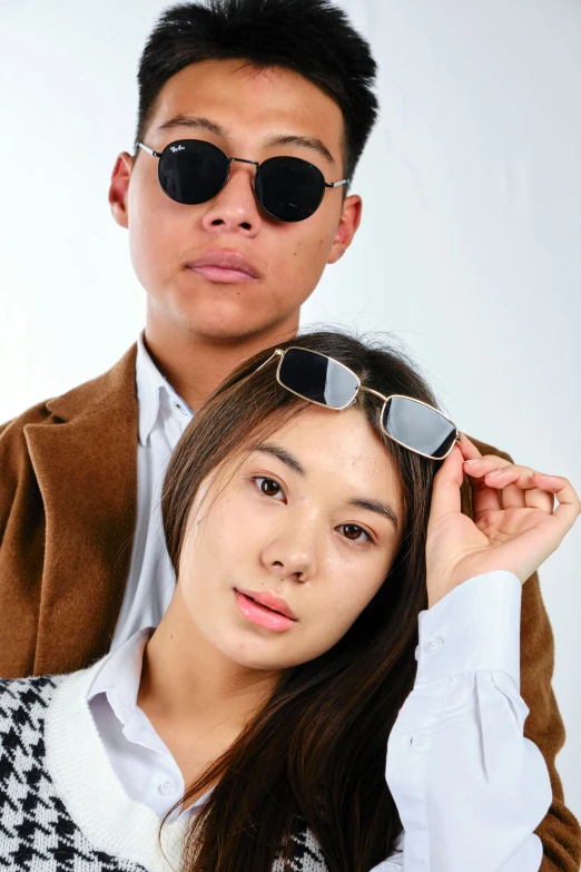 a man and a woman posing for a picture, wear ray - ban glass, half asian, at a fashion shoot, promotional image