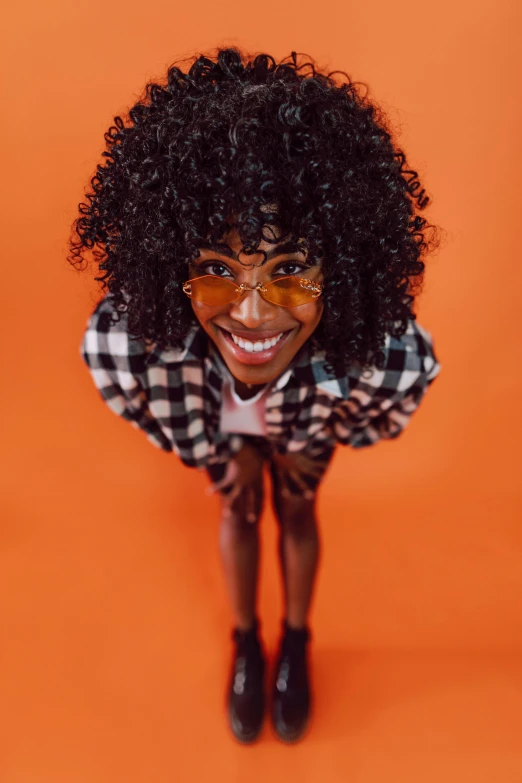a woman wearing glasses and a checkered shirt, trending on pexels, afrofuturism, fluffy orange skin, smiling down from above, 🍂 cute, in a halloween style