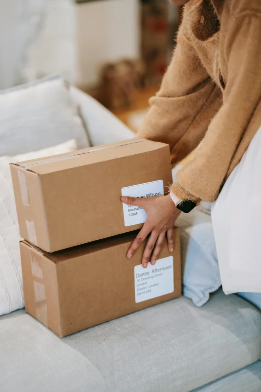 a woman sitting on a couch holding two boxes, by Eden Box, selling insurance, labels, manuka, thumbnail