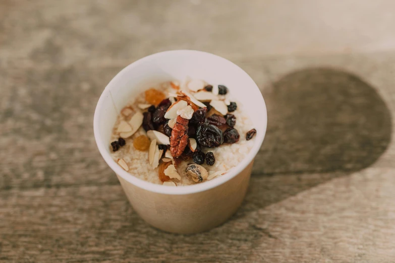 a cup of oatmeal with raisins and nuts, unsplash, built on a small, exterior shot, carefully crafted, unfinished