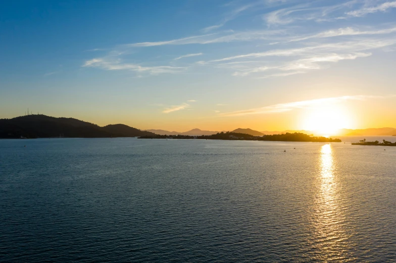 the sun is setting over a body of water, pexels contest winner, island in the background, golden hour 8k, essence, ultrawide shot