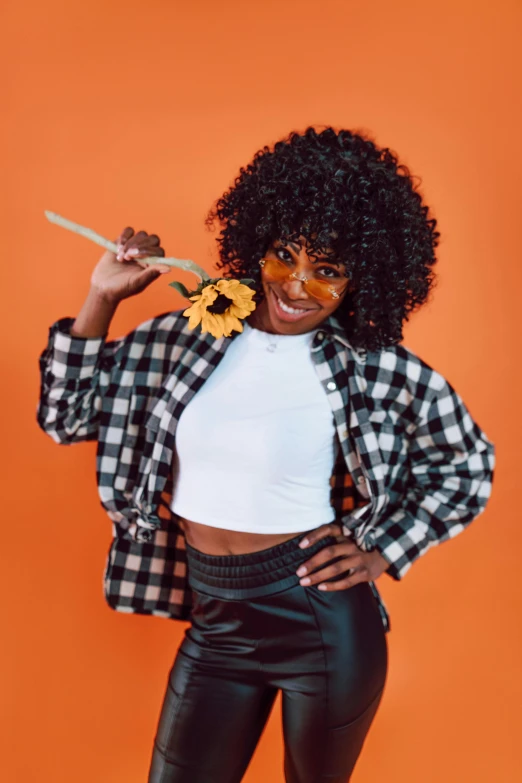 a woman in a plaid shirt and leather pants, trending on pexels, afro made of flowers, 🍂 cute, orange glow, power pose