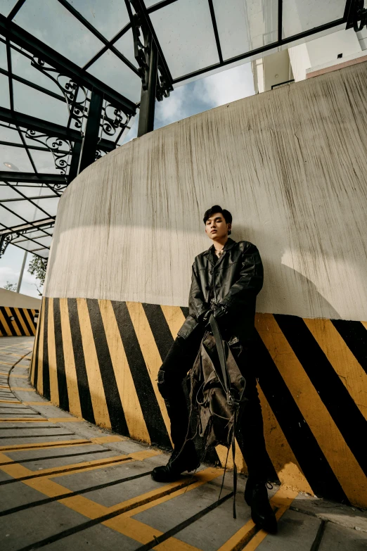 a man in a leather jacket leaning against a wall, an album cover, inspired by Zhang Han, unsplash, conceptual art, wearing long gown, runway photo, on rooftop, stood in a tunnel