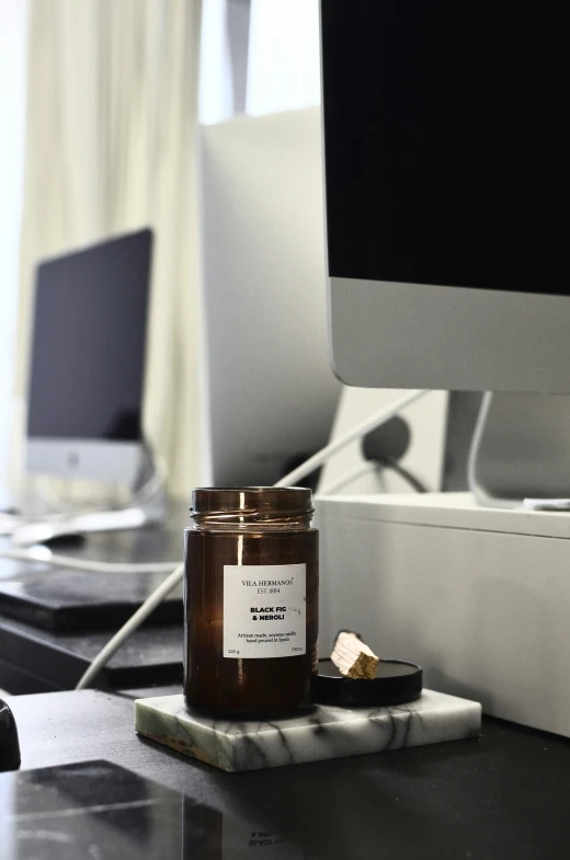 a glass jar sitting on top of a desk next to a computer, waxy candles, profile image, detailed product image, environmental shot