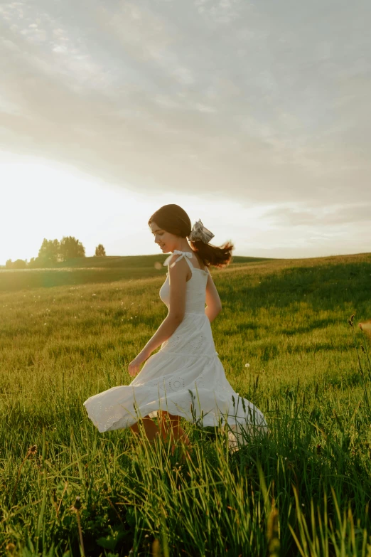 a woman in a white dress walking through a field, serene field setting, running freely, warmly lit, 2019 trending photo