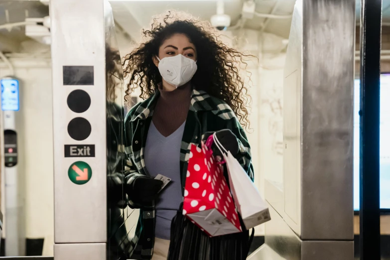 a woman wearing a face mask and carrying shopping bags, by Dan Frazier, pexels, in an elevator, square, ashteroth, holiday