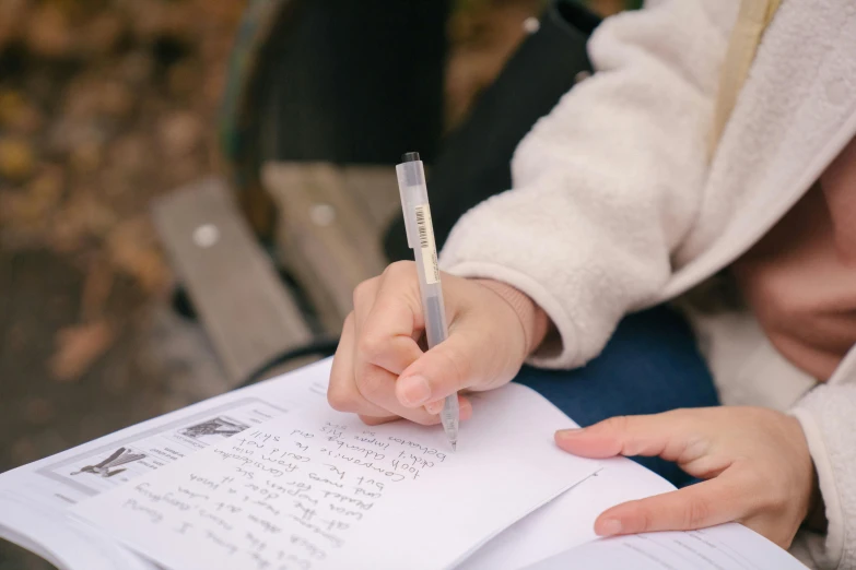 a person sitting on a bench writing on a piece of paper, diary on her hand, holding an epée, a close up shot, on medium grade paper