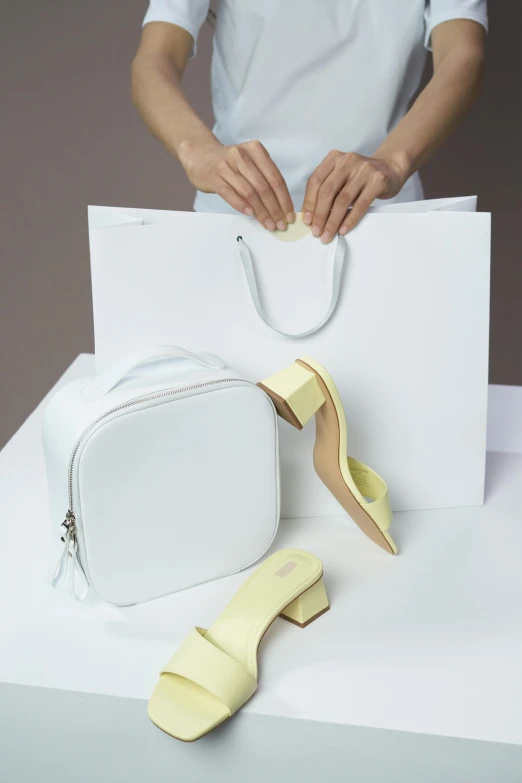 a woman holding a white bag next to a pair of yellow shoes, soft shapes, collection product, pastel', stores