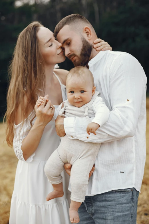 a man and woman holding a baby in a field, pexels contest winner, white clothes, square, extremely handsome, low quality photo