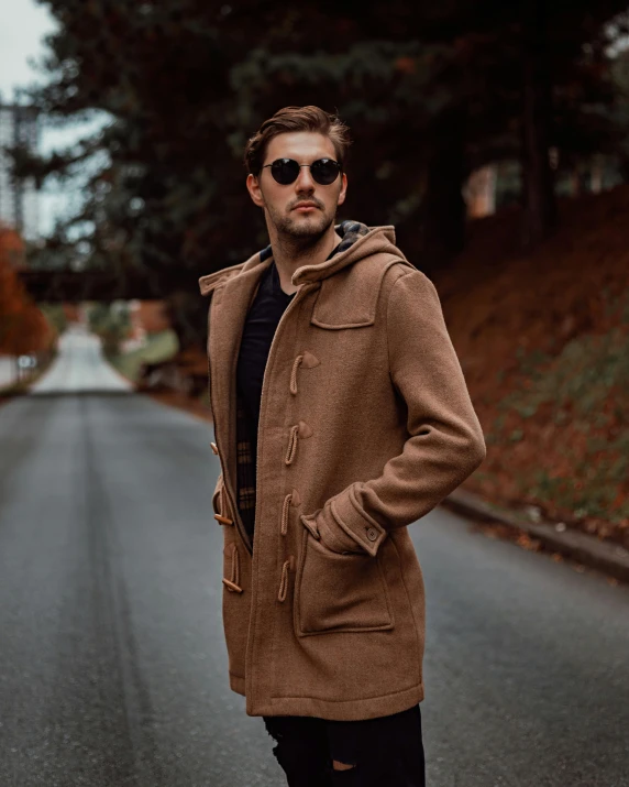 a man standing in the middle of a road, an album cover, inspired by Alexander Sharpe Ross, unsplash contest winner, photorealism, brown tuffle coat, mid-shot of a hunky, with two front pockets, male model