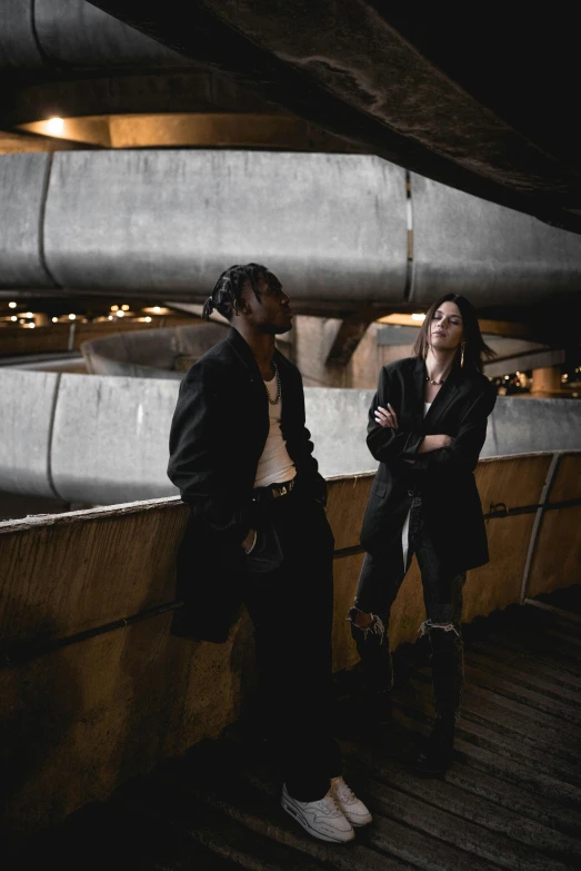 two people standing next to each other on a bridge, an album cover, pexels contest winner, travis scott, in an underground parking garage, fashion shoot 8k, dark people discussing