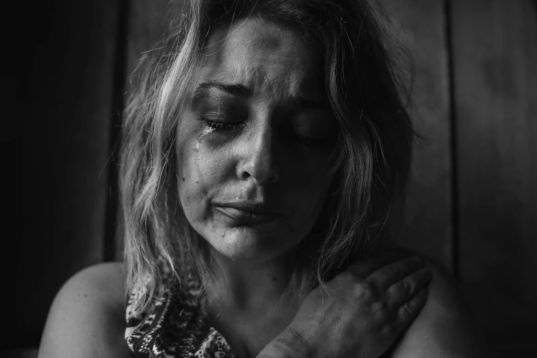 a black and white photo of a woman with tears on her face, pexels, renaissance, hugging her knees, 268435456k film, blonde woman, injured